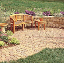 Yellow and rust colored circular patio pavers with retaining wall